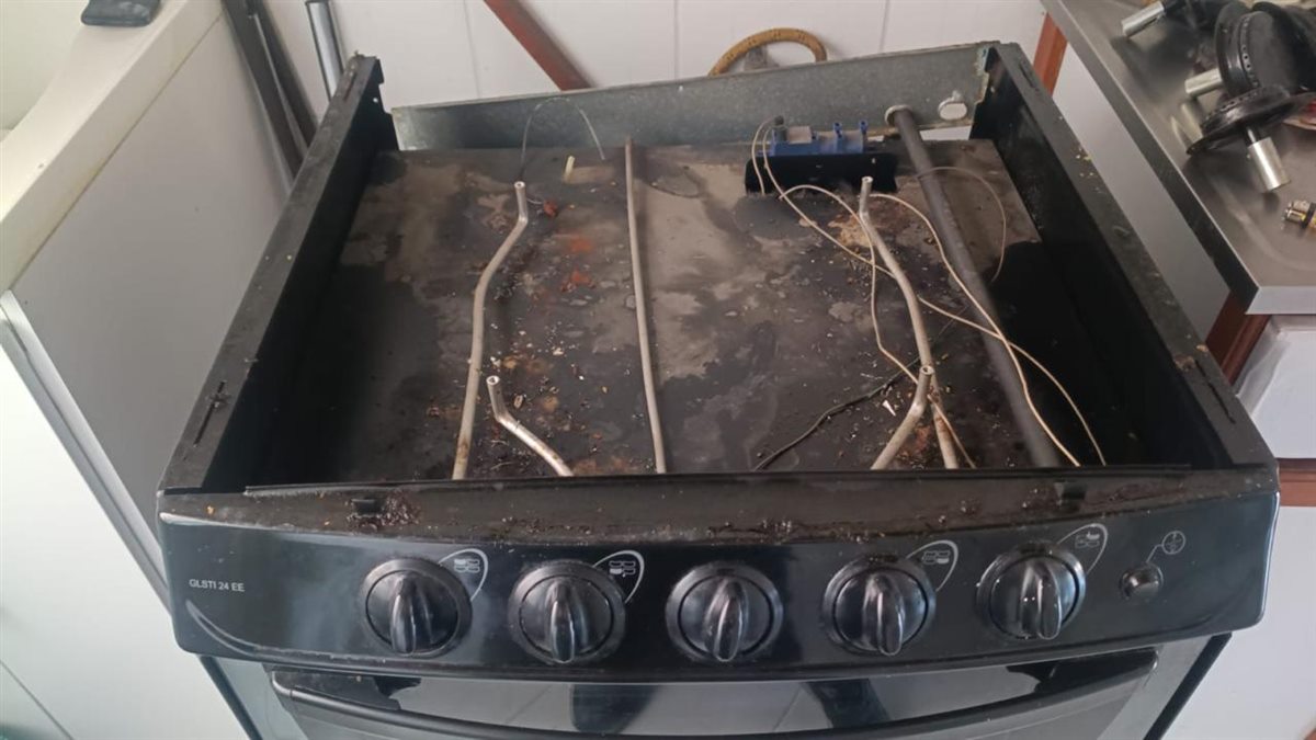 Estufa Icasa a gas de más de 25 años con la cubierta abierta en El Poblado: bandeja con grasa y residuos acumulados, conductos de gas y cables del encendido
